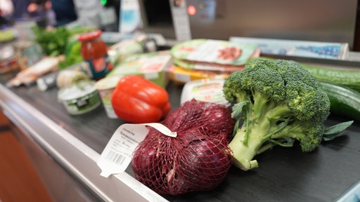Lebensmittel liegen auf dem Laufband an einer Kasse in einem Supermarkt.