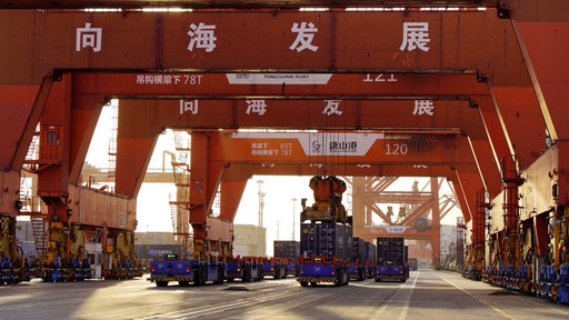 Unbemannte Fahrzeuge fahren unter Containerbrücken am Containerterminal des Hafens bei Tangshan in der nordchinesischen Provinz Hebei. 