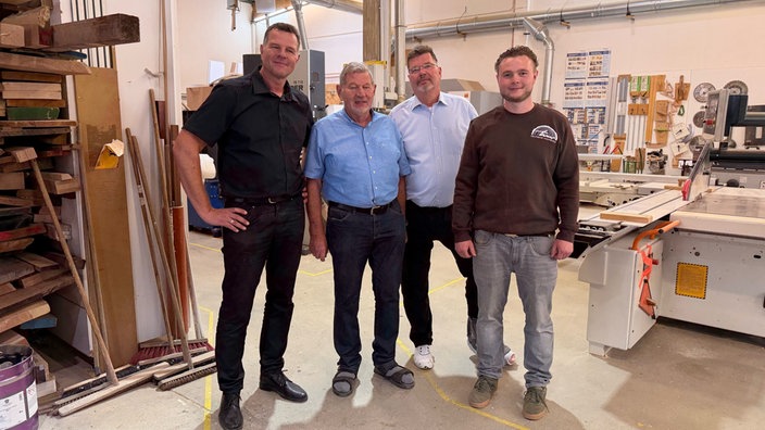 Vier Männer stehen in einer Werkstatt