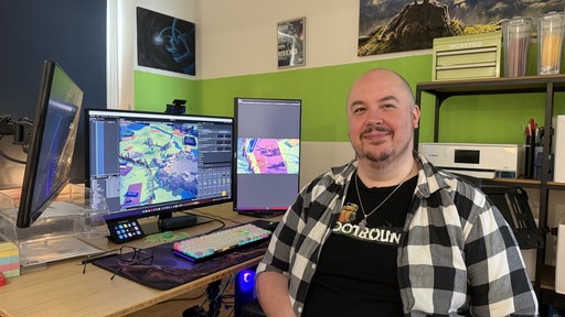 Portrait eines Games-Entwicklers vor mehreren Monitoren.
