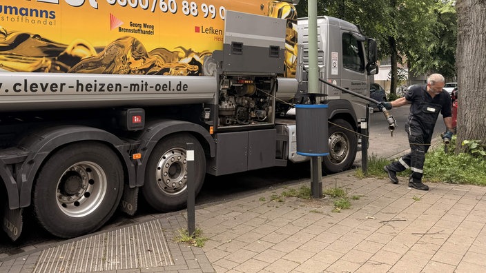 Mann zieht Schlauch für Heizölbefüllung