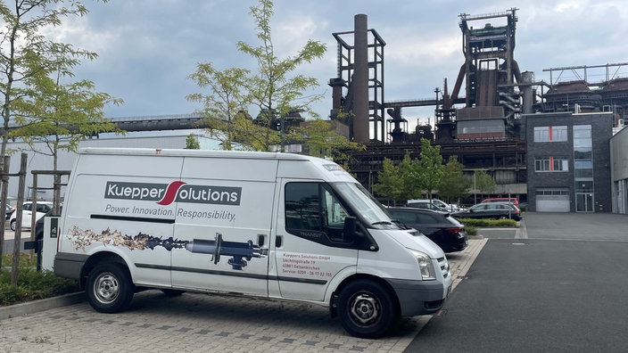Ein weißer Lieferwagen mit der Aufschrift "Kuepper Solutions", darunter ein gerät, das eine Art Flamme speit.