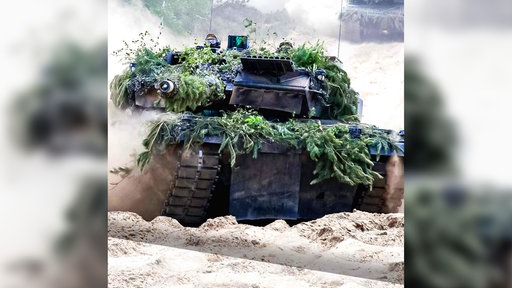 Ein Panzer fährt mit seinen Ketten durch den Sand