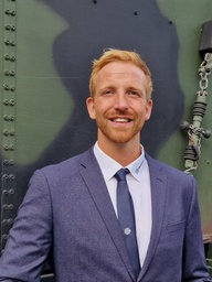Ein Mann im Anzug steht vor einem Militärlaster.