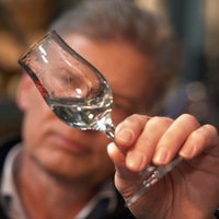 Ein Mann Hält ein Schnapsglas vor sein Gesicht und betrachtet die Flüssigkeit