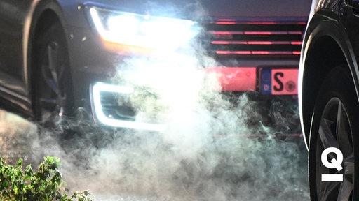 Autos stehen im Stau und stoßen Abgase in die Luft. Es ist dunkel und die Scheinwerfen des hinteren Autos leuchten hell. 