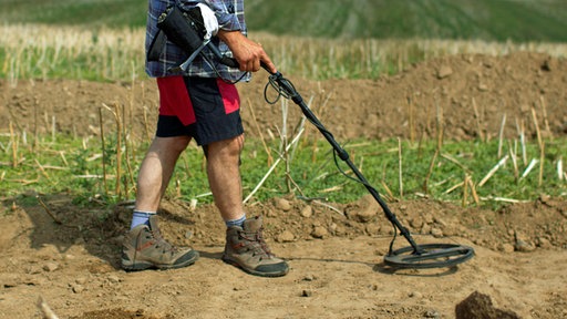 Man sucht ein Feld mit Metalldetektor ab