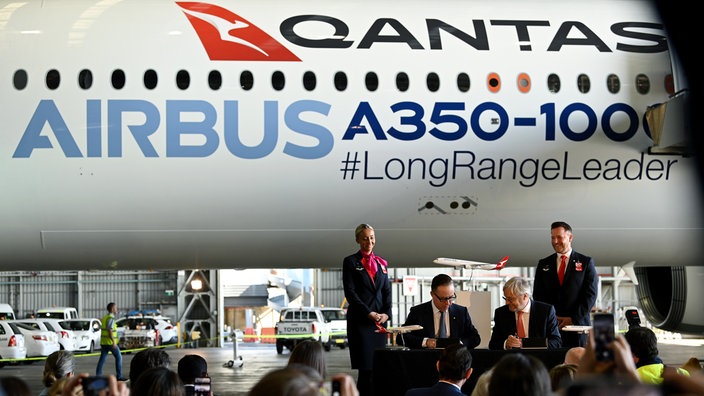 Vertreter von Qantas und Airbus bei einer Vertragsunterzeichnung auf einem Rollfeld