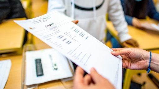 Die Klassenlehrerin übergibt das Zeugnis eines Schülers