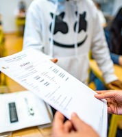 Die Klassenlehrerin übergibt das Zeugnis eines Schülers